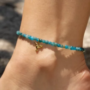 bracelet de cheville en apatite bleue avec charm colibri. Photo du bijou porté par une modèle