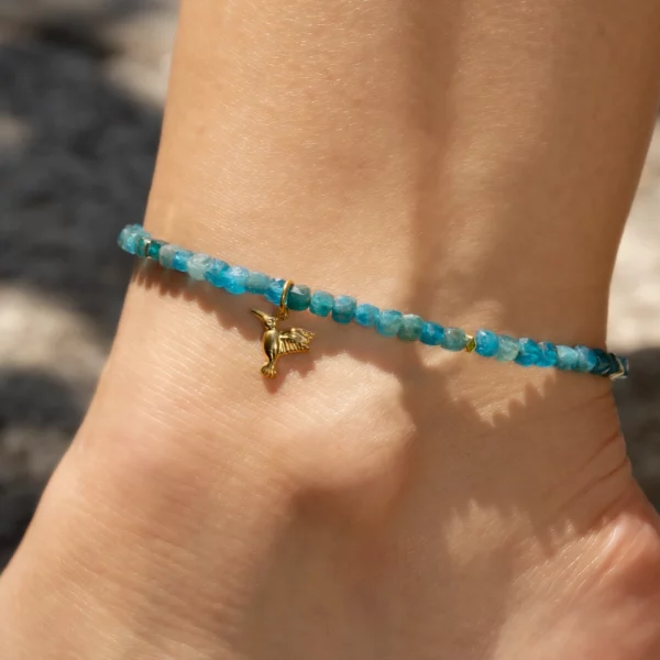 bracelet de cheville en apatite bleue avec charm colibri. Photo du bijou porté par une modèle