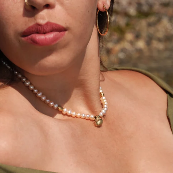 collier en perles blanches avec charm coquillage photo porté par une modèle