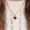 pendentif en forme de coeur en or et oeil de tigre. photo porté par modèle